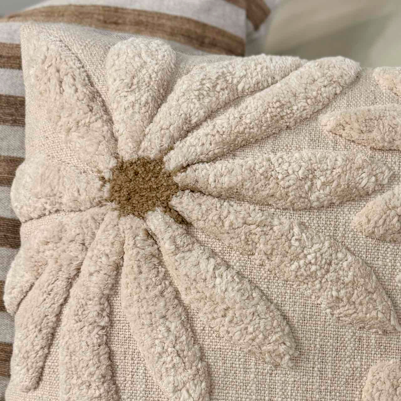 Textured pillow with a starburst pattern in neutral tones