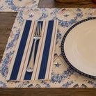 Placemat with blue and white floral pattern, red and white striped area, and silver fork on a wooden surface.