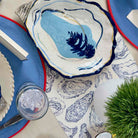 Table setting with oyster-themed plates and a blue and white patterned tablecloth.