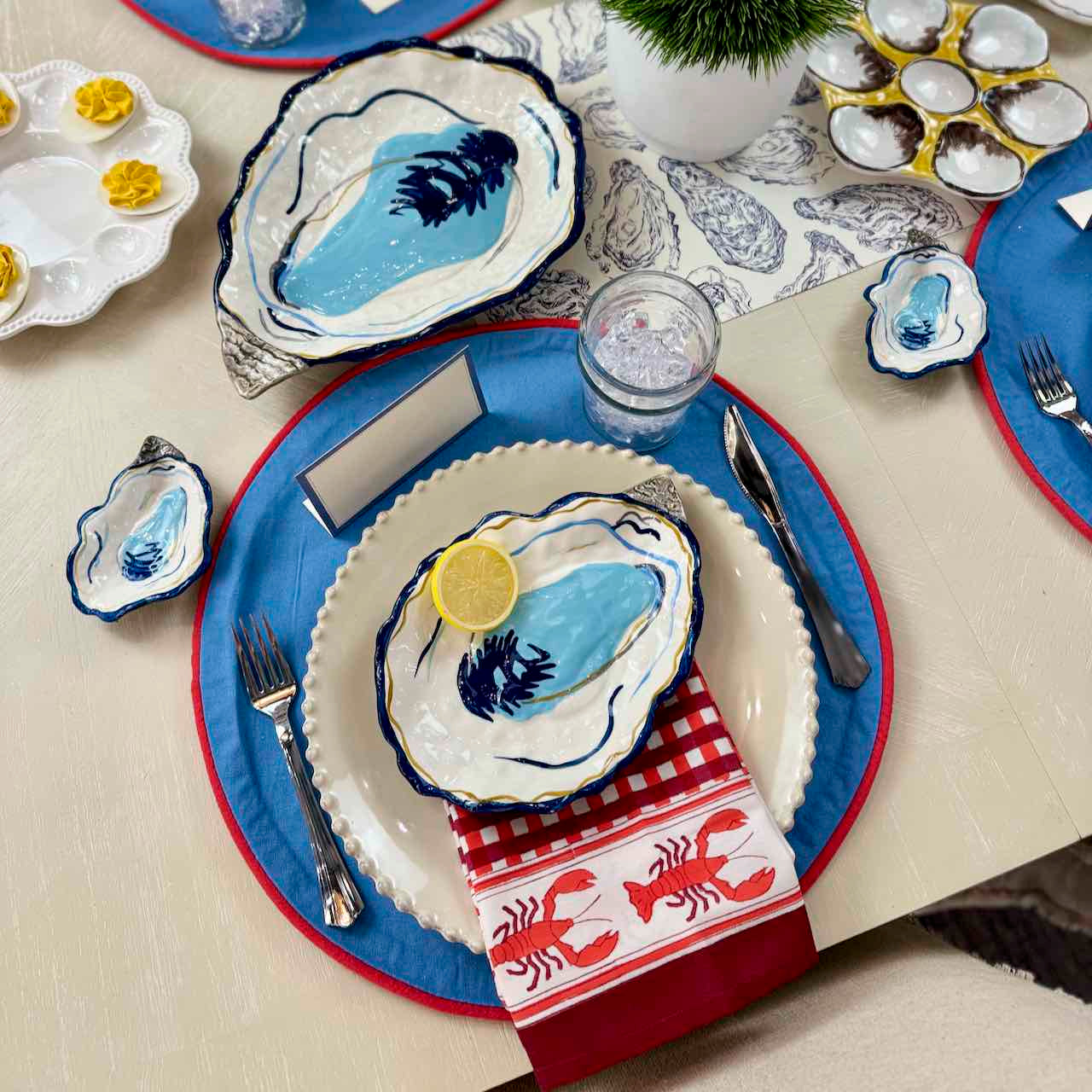 Nautical-themed table setting with oyster shells and blue plates on a white tablecloth.