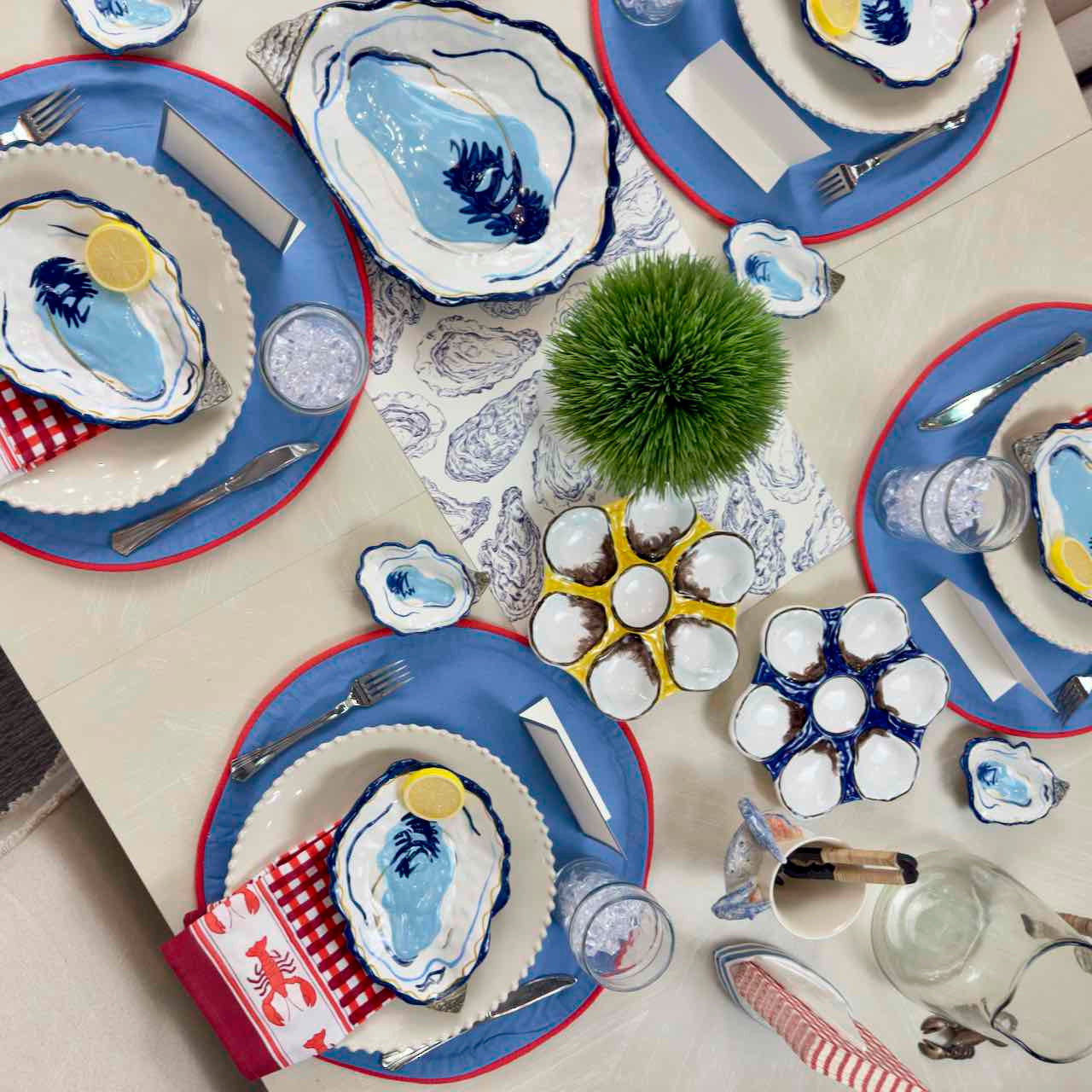 Table setting with blue and white plates, silverware, and decorative elements on a white table.