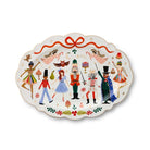 An oval ceramic serving platter with a scalloped edge, decorated with a festive Nutcracker theme featuring illustrated figures, ornaments, candy canes, and a red ribbon at the top, on a white background.
