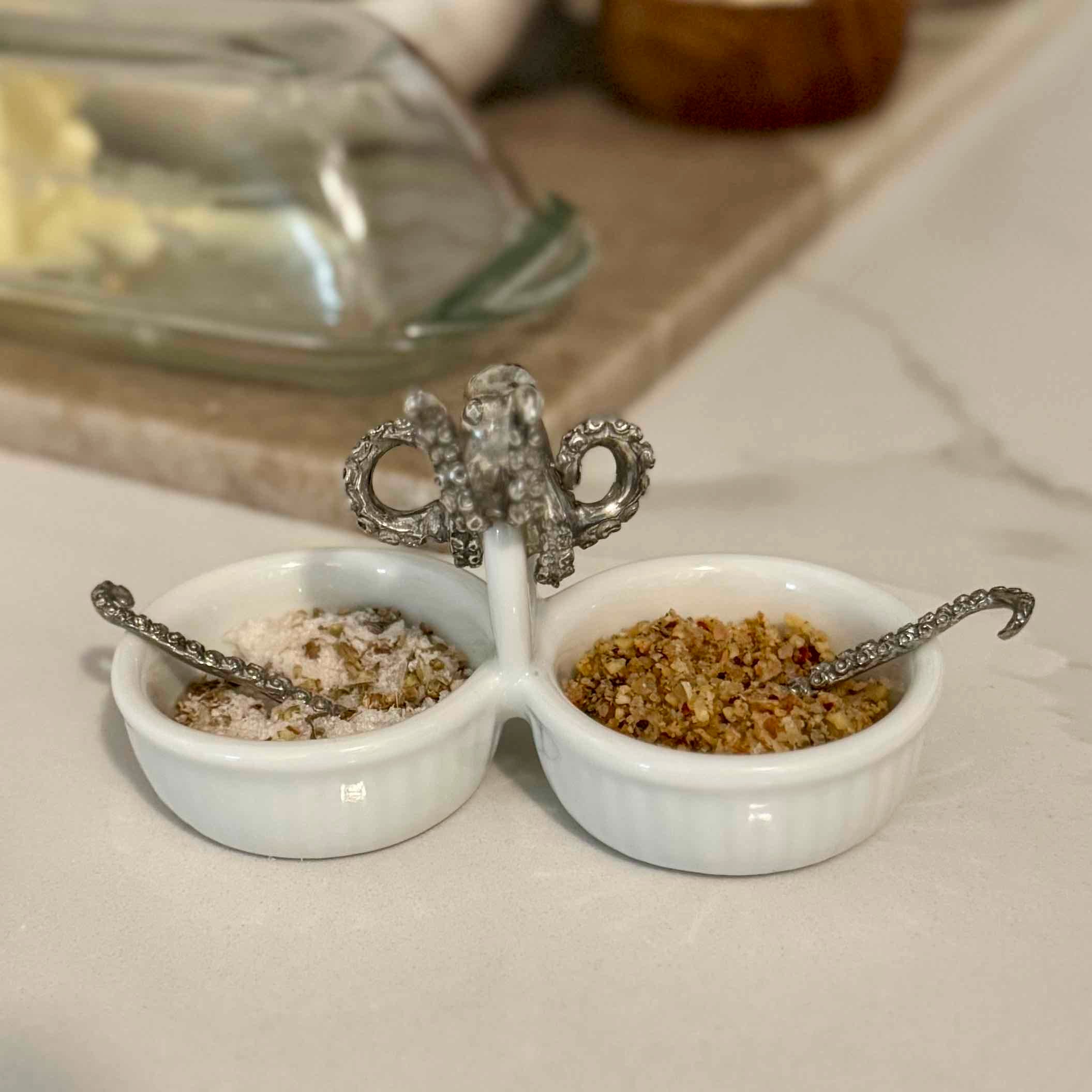 White ceramic salt and pepper shaker set with decorative silver tops on a neutral background.