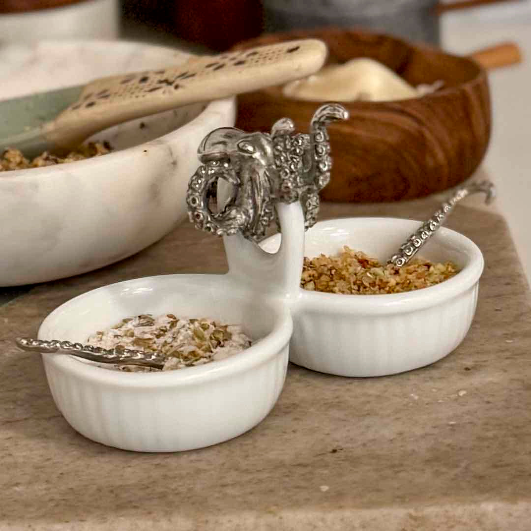 Two white ceramic bowls with decorative spoons on a wooden surface.