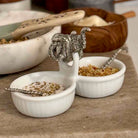 Two white ceramic bowls with decorative spoons on a wooden surface.