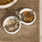 Two small white bowls with silver elephant handles on a textured surface.