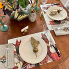 Thanksgiving table setting with place mats, plates, and decorative items on a wooden table.