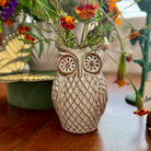 Ceramic owl vase with flowers on a wooden surface