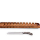 An oval-shaped wooden bread board with slots for slicing bread, accompanied by a knife with a pewter antler handle.