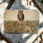 Small tin box with an owl design on a textured surface