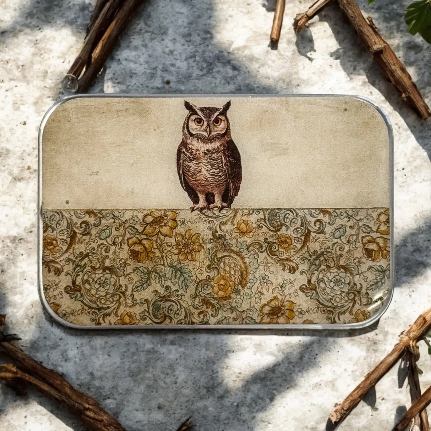 Small tin box with an owl design on a textured surface