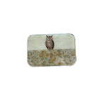 A small rectangular tin with rounded corners, featuring an owl illustration on a cream background with a floral patterned lower half, placed on a light wood surface.
