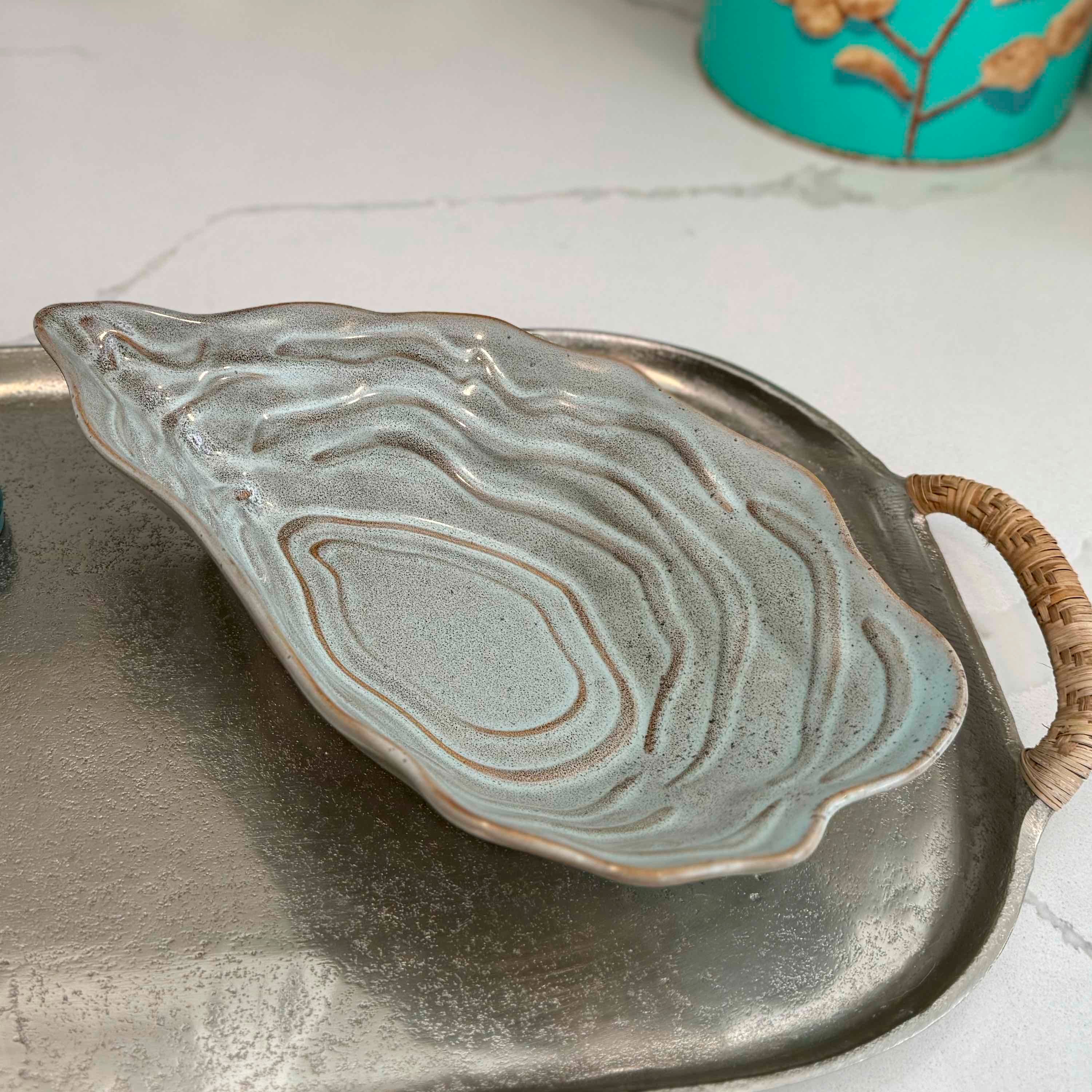 Ceramic leaf-shaped dish on a metal tray with a marble background
