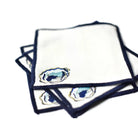 Set of white napkins with blue border and decorative emblem on a white background
