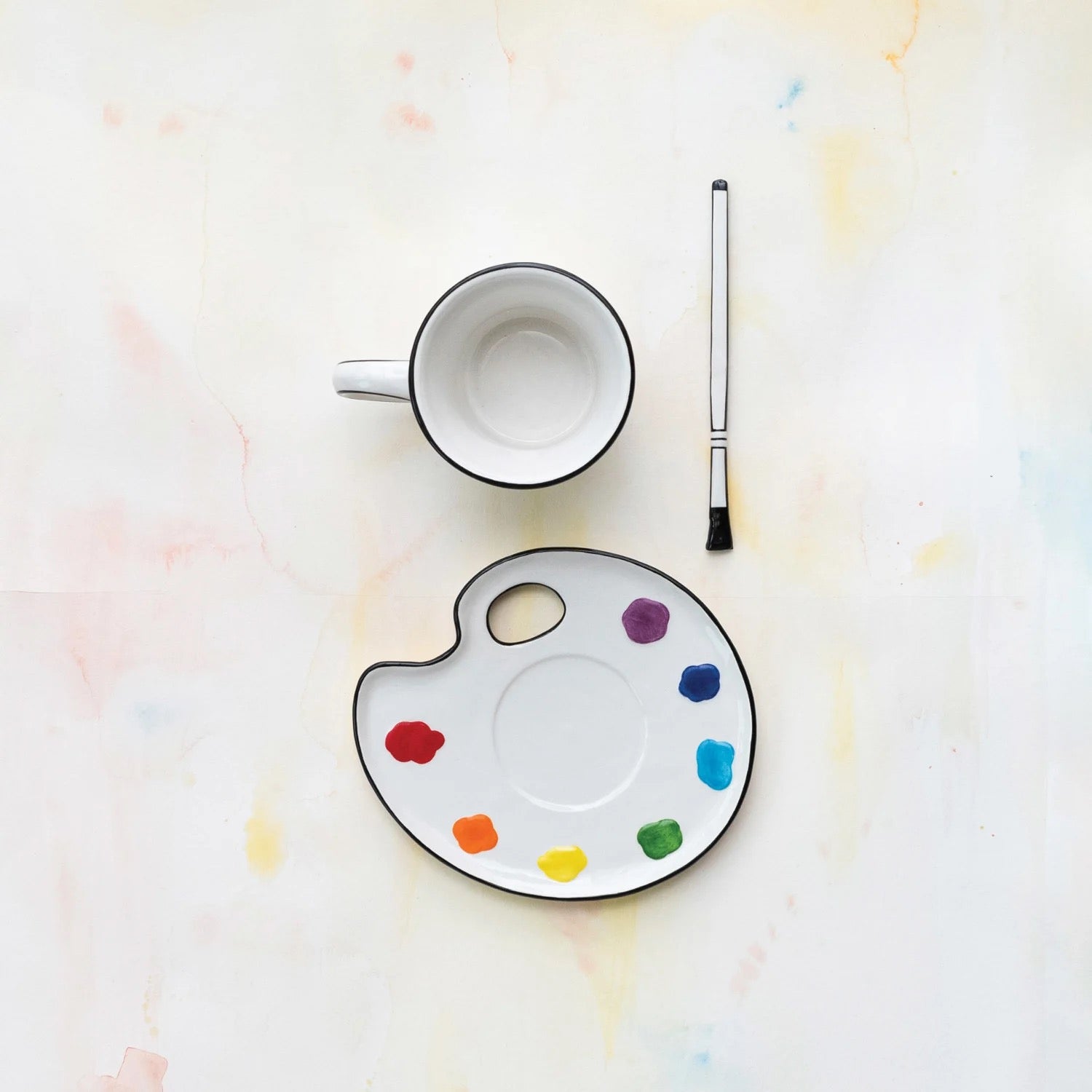 Empty mug, paintbrush, and color palette on a light background