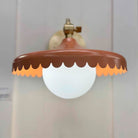Decorative wall light fixture with scalloped brown shade on a plain background