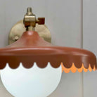 Wall-mounted light fixture with a brown scalloped shade on a neutral background