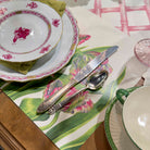 Table setting with floral plates, silverware, and a colorful placemat.