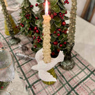 Decorative candle with angel ornament on a table with Christmas decorations in the background