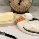 Decorative pelican saltshaker on a kitchen counter with butter and a knife.