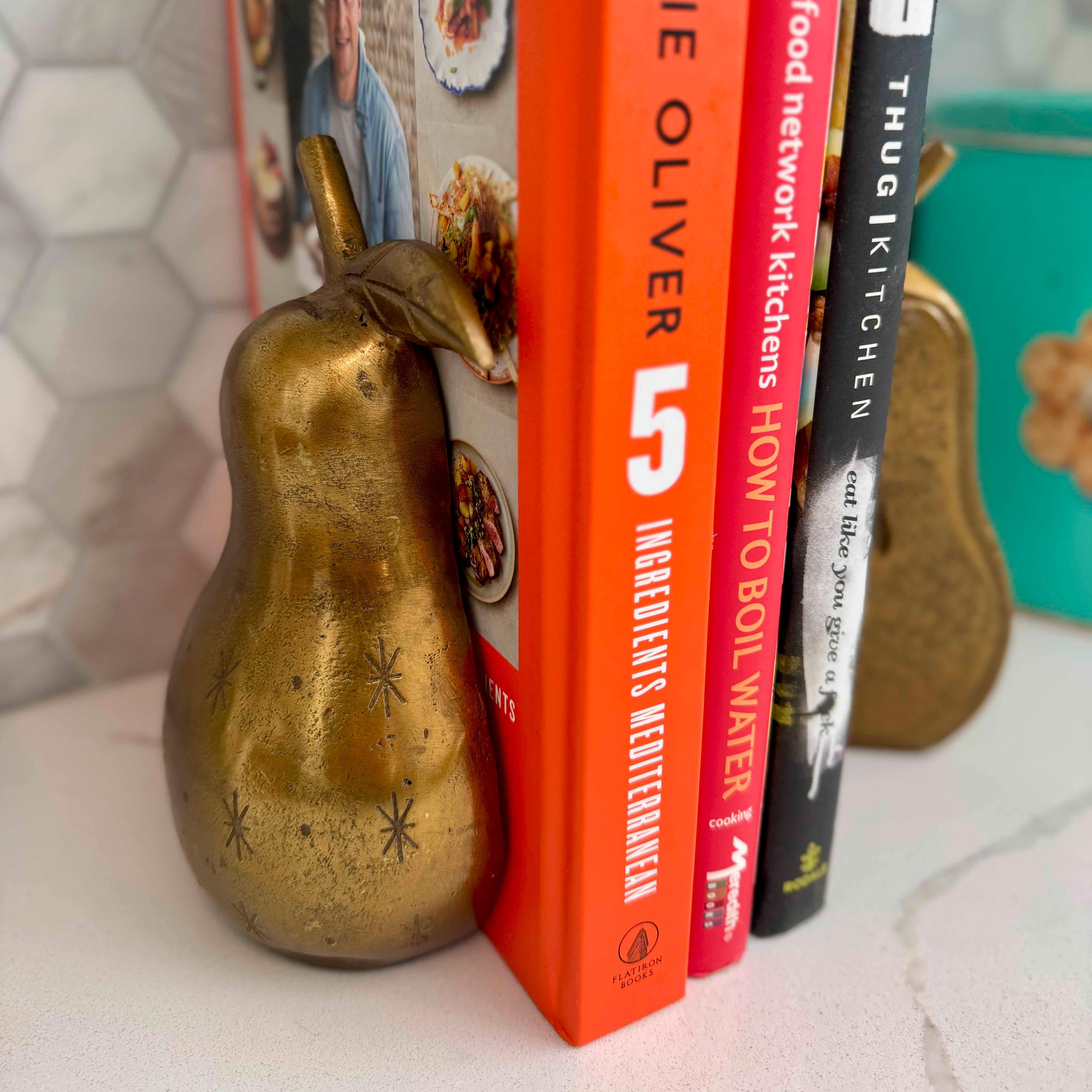 Three cookbooks stacked with decorative gourds on a surface
