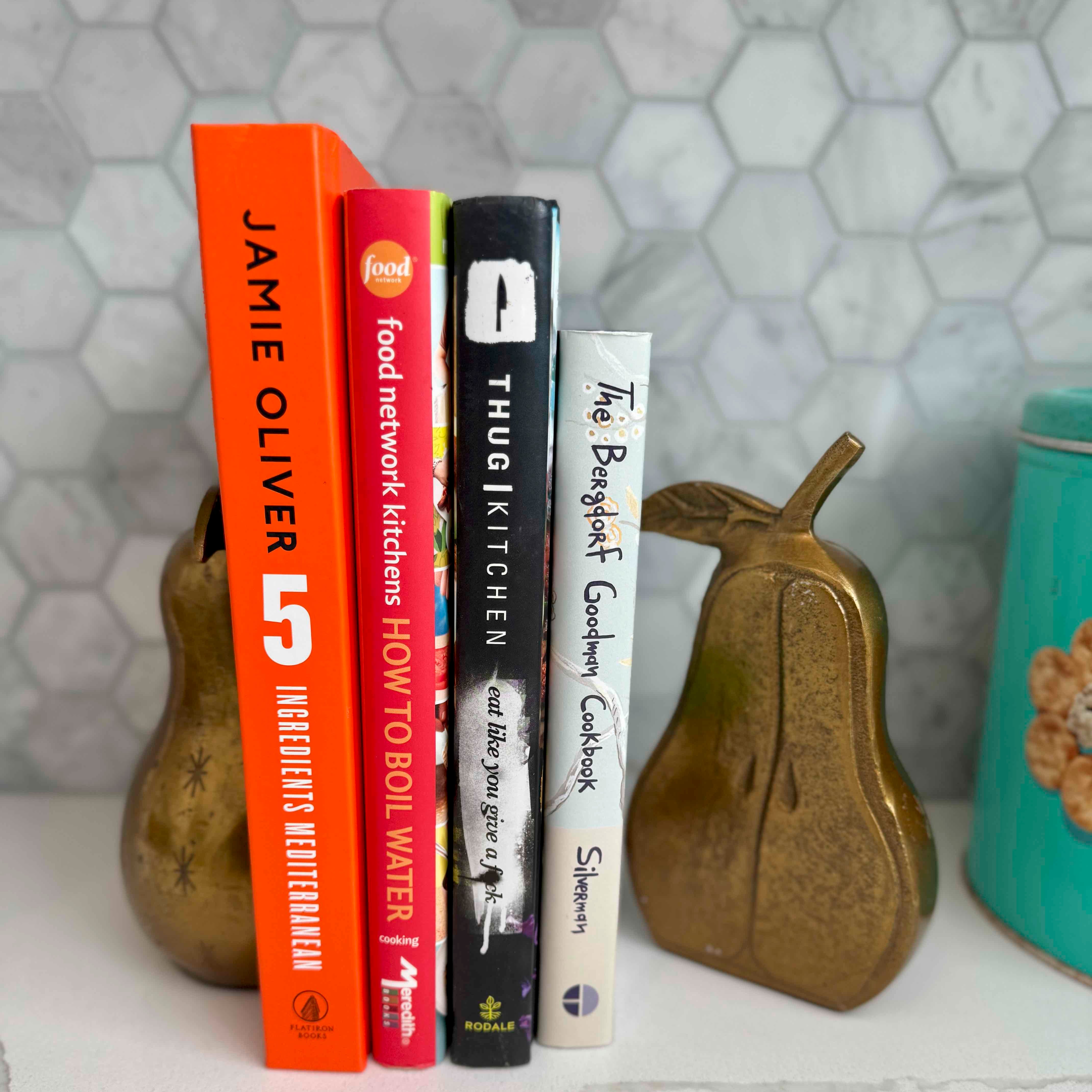 Stack of cookbooks with decorative pears on a textured surface