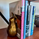 Row of books on a wooden surface with a gold pear-shaped object in front