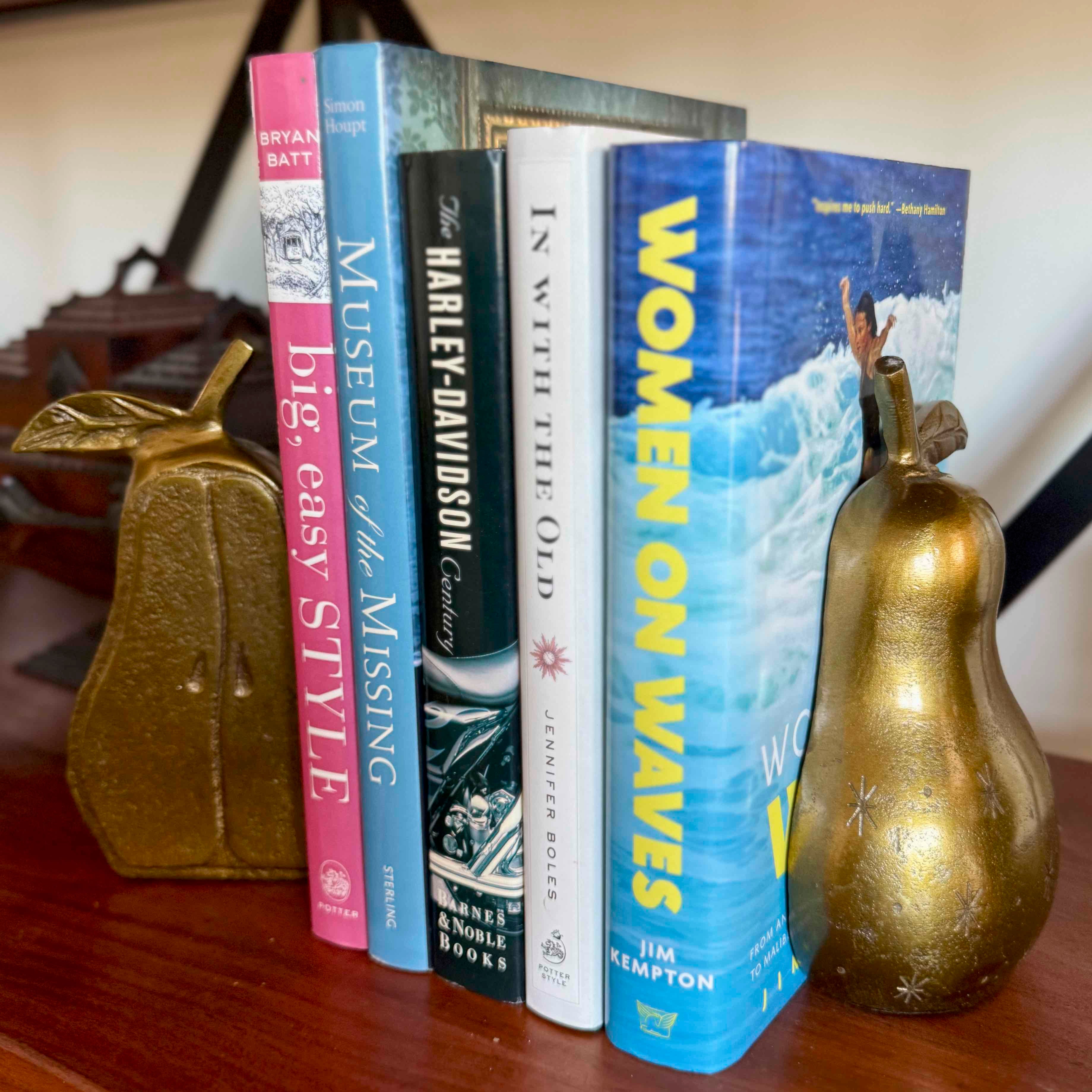 Stack of books on a surface with decorative gourds on either side.