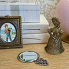 Decorative items including a small round mirror, a figurine, and a framed picture on a surface.