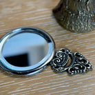 Compact mirror with decorative frame on a wooden surface