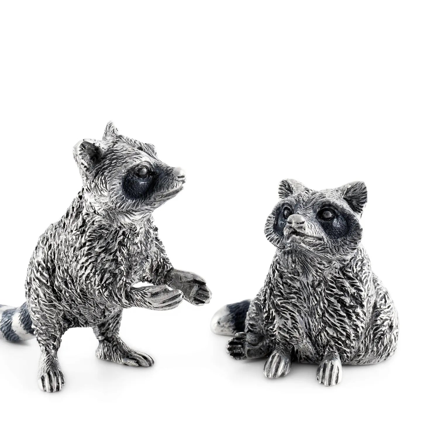 Two silver raccoon figurines on a white background
