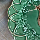 Decorative green ceramic plate with floral patterns on a wooden surface