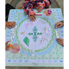 People playing a board game with a decorative game board on a table.
