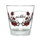 A clear glass shot glass featuring a red floral wreath design with the word 'pickled' written in black script in the center, shown against a plain white background.