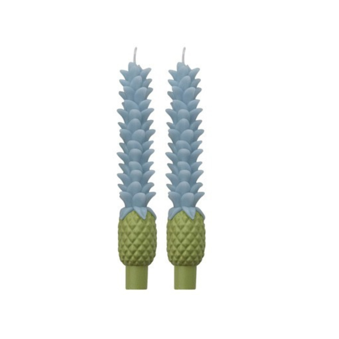 Two pineapple-shaped candles on a white background