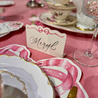 Decorative table setting with a 'Meryl' card on a pink tablecloth.