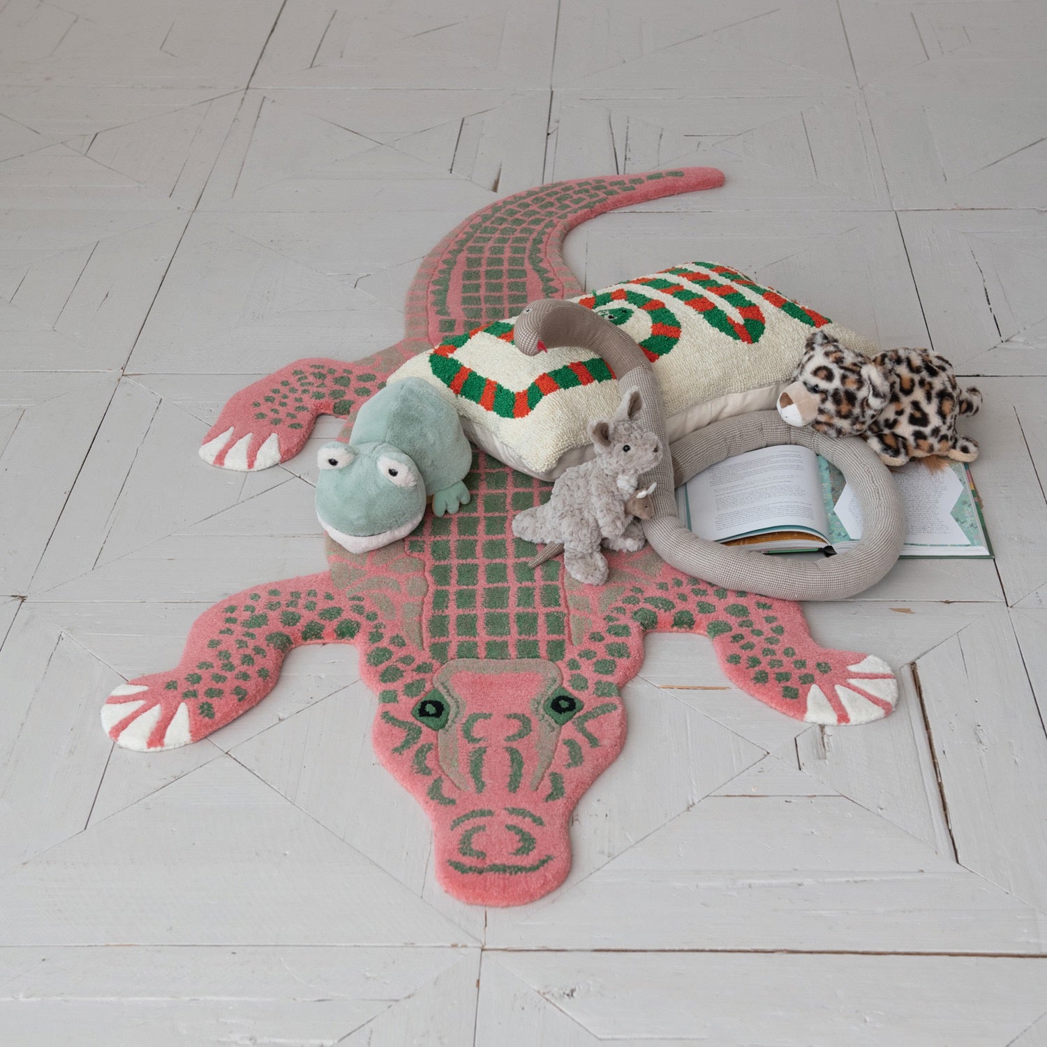 Children's rug shaped like a crocodile with plush toys on a light wooden floor