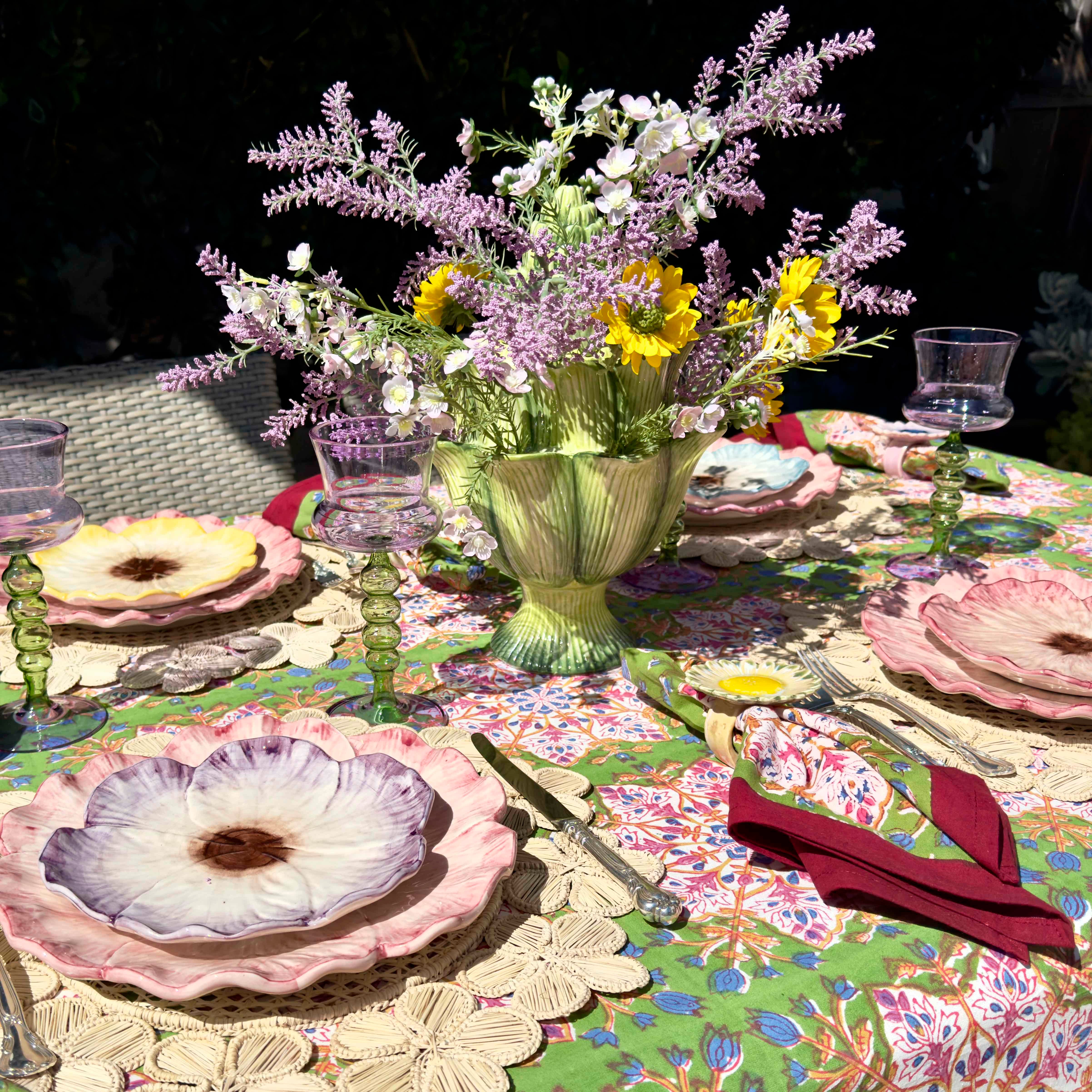 Decorative table setting with floral centerpiece, colorful plates, and patterned tablecloth.