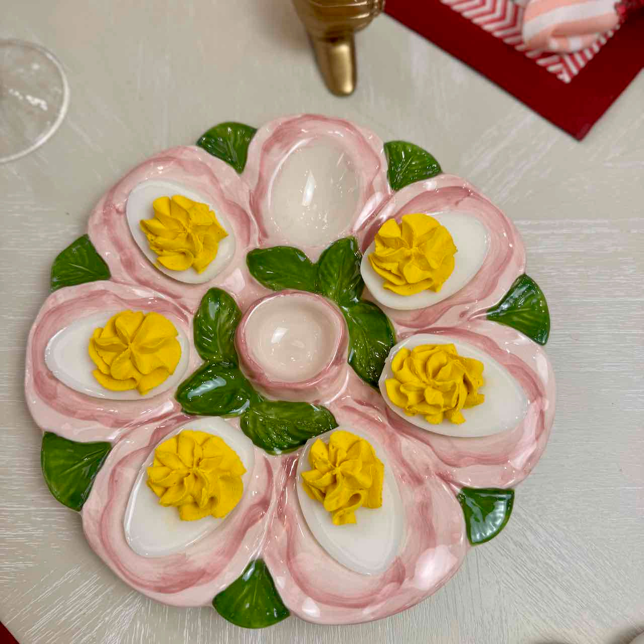 Decorative arrangement of deviled eggs on a plate with pink and green garnishes.