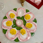 Decorative arrangement of deviled eggs on a plate with pink and green garnishes.