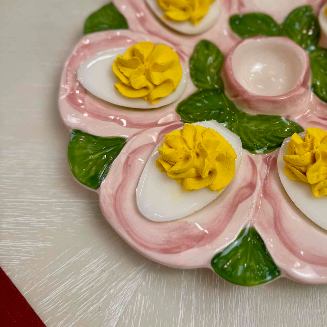Decorative plate with deviled eggs, pickles, and yellow flowers on a light background