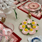 Decorative table setting with a plate of deviled eggs and flowers, wine glasses, and place cards.