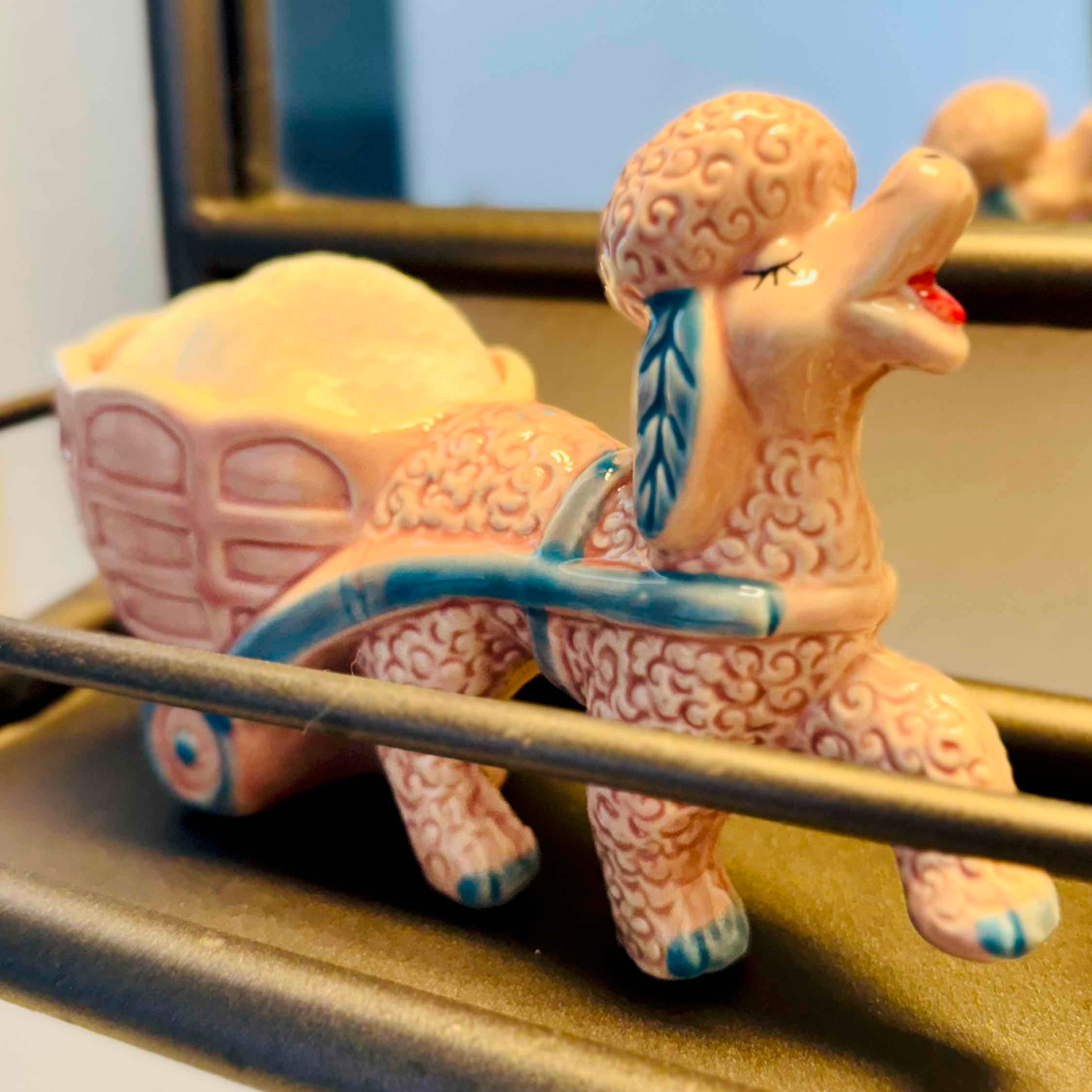 Ceramic figure of a tortoise pulling a cart with a small figure on top, set against a neutral background.