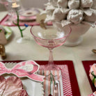Pink glass on a decorated table with floral arrangements and place settings.