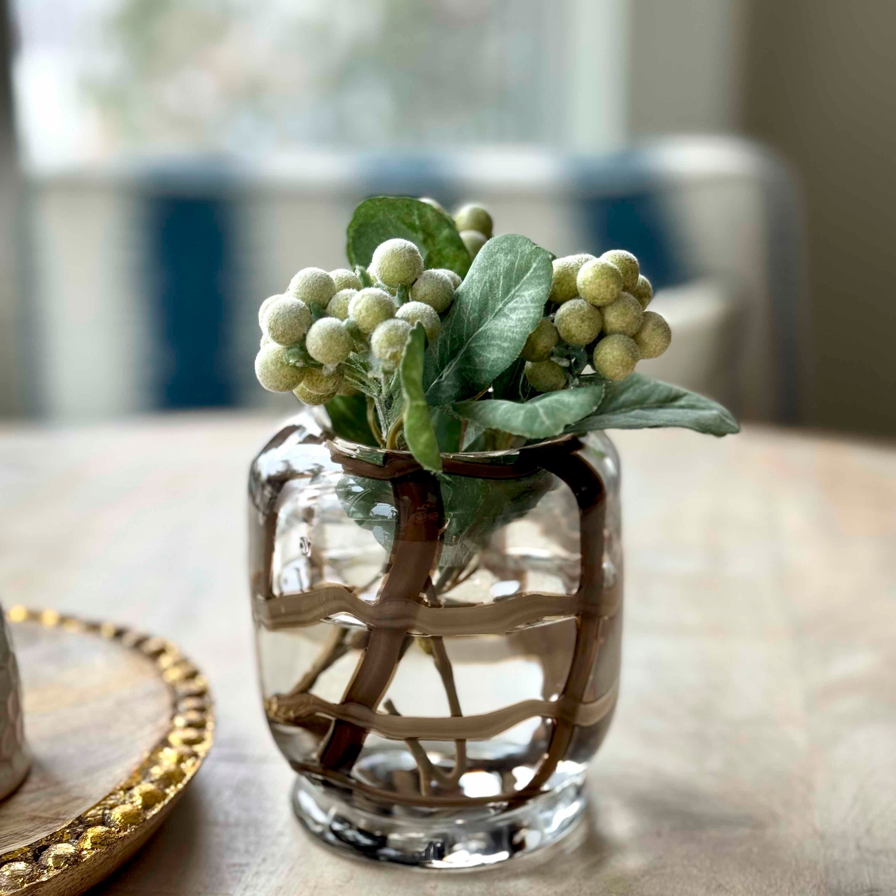Clear glass vase with greenery on a table
