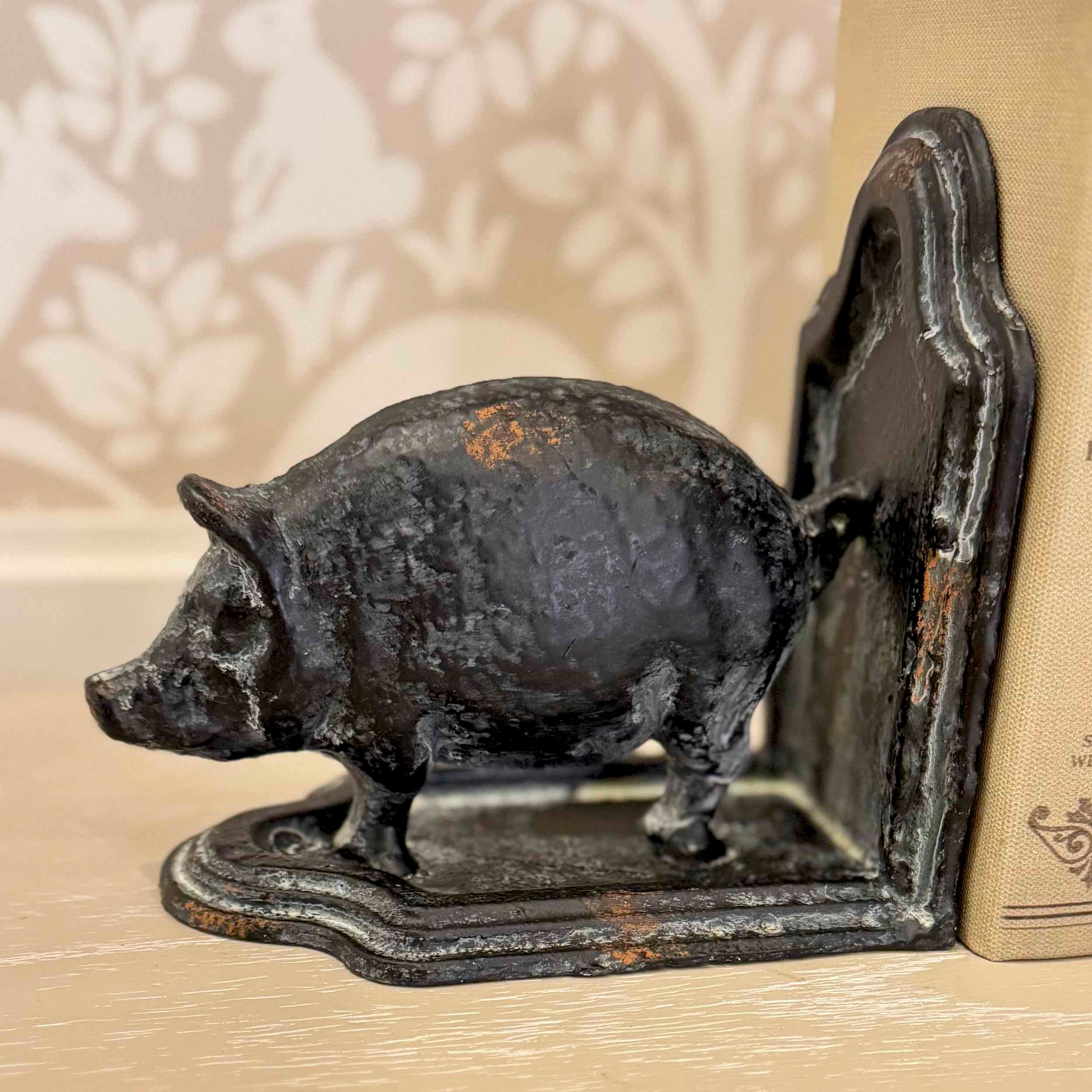Cast iron pig bookend on a wooden surface with a blurred background