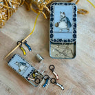 Small tin with sewing supplies including pins and needles, on a wooden surface.