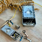 Small metal tin with sewing supplies on a wooden surface