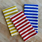 Three striped towels in green, red, and blue on a wooden surface