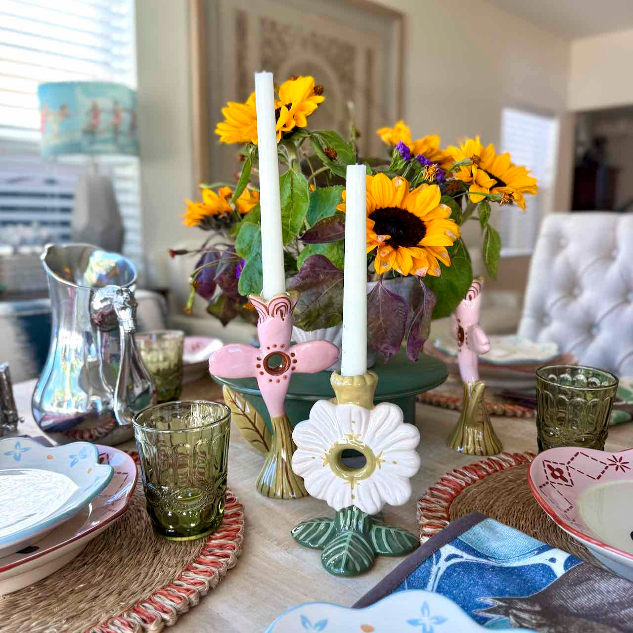 Decorative table setting with sunflowers, candles, and colorful tableware.